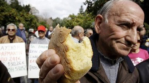 Một người về hưu tại Hy Lạp cầm mẩu bánh mì trong cuộc biểu tình bên ngoài phủ thủ tướng vào ngày 3-3 để phản đối kế hoạch thắt lưng buộc bụng của chính phủ - Ảnh: AP.